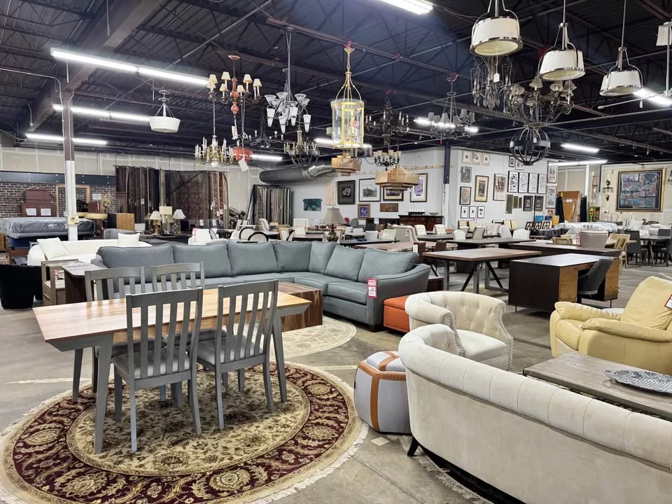 Blue sectional, dining sets, and chandeliers under warehouse lighting at Unique Furniture Warehouse, Twin Cities furniture outlet