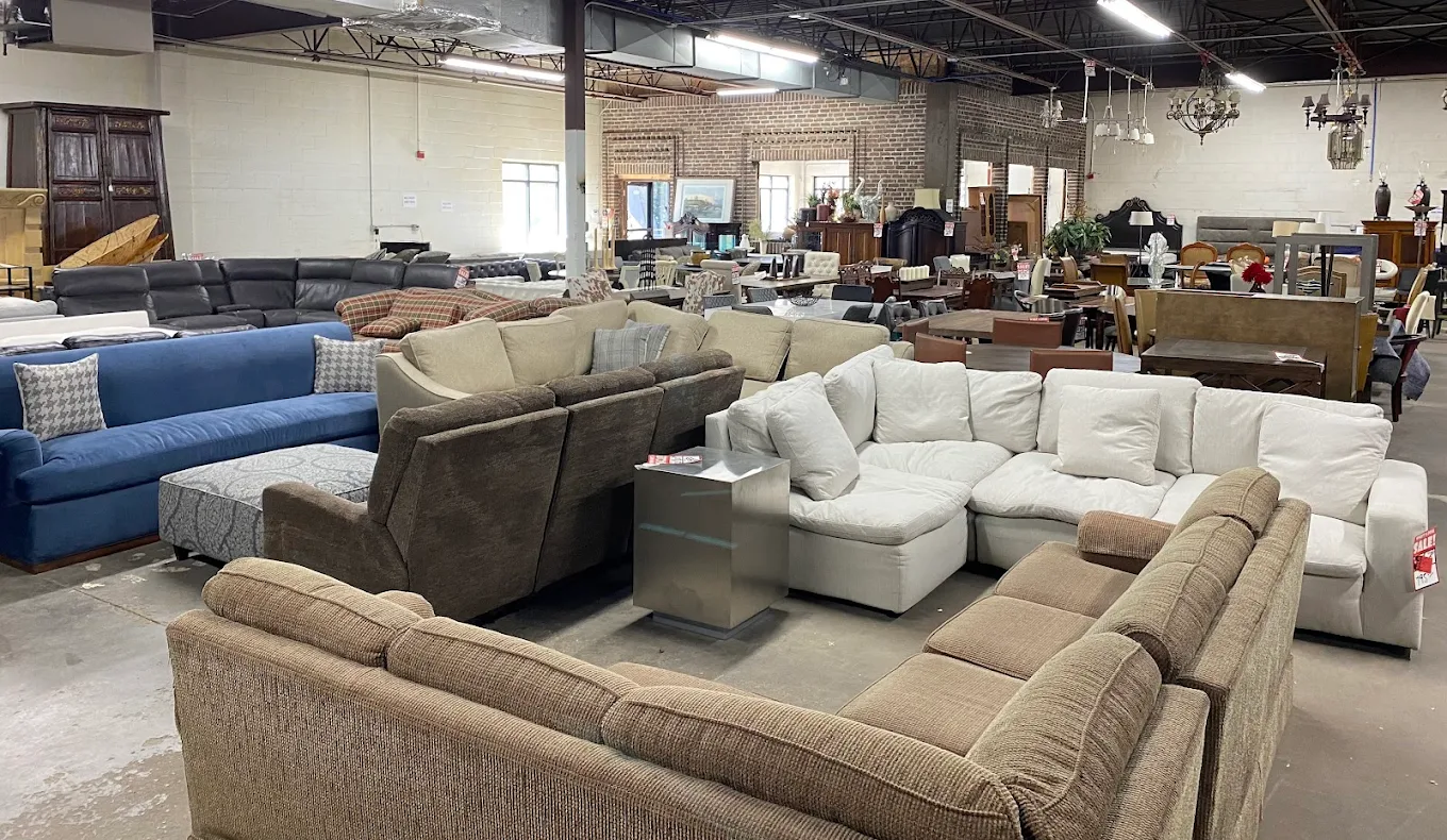Measuring the depth of a sofa with a tape measure at a furniture warehouse