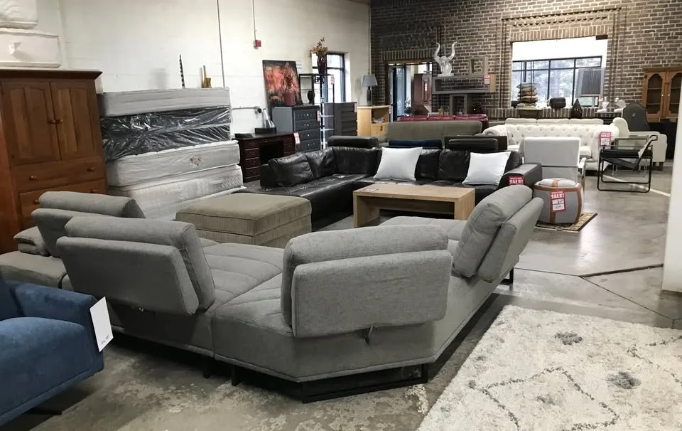 Gray fabric sectional and leather sectional staged near a brick wall at Unique Furniture Warehouse, Twin Cities furniture outlet